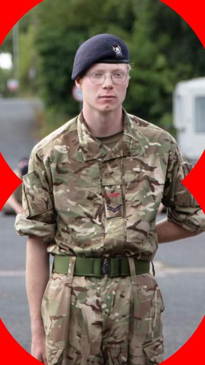 A man in Army uniform with his left hand behind his back. He is wearing glasses.