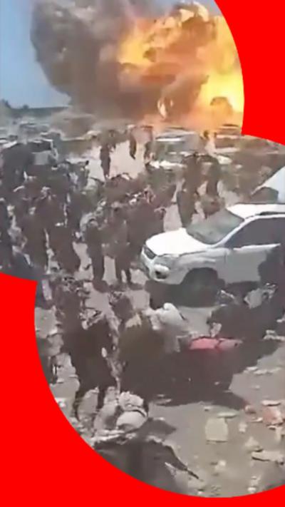 People running past a car with an explosion in the background 