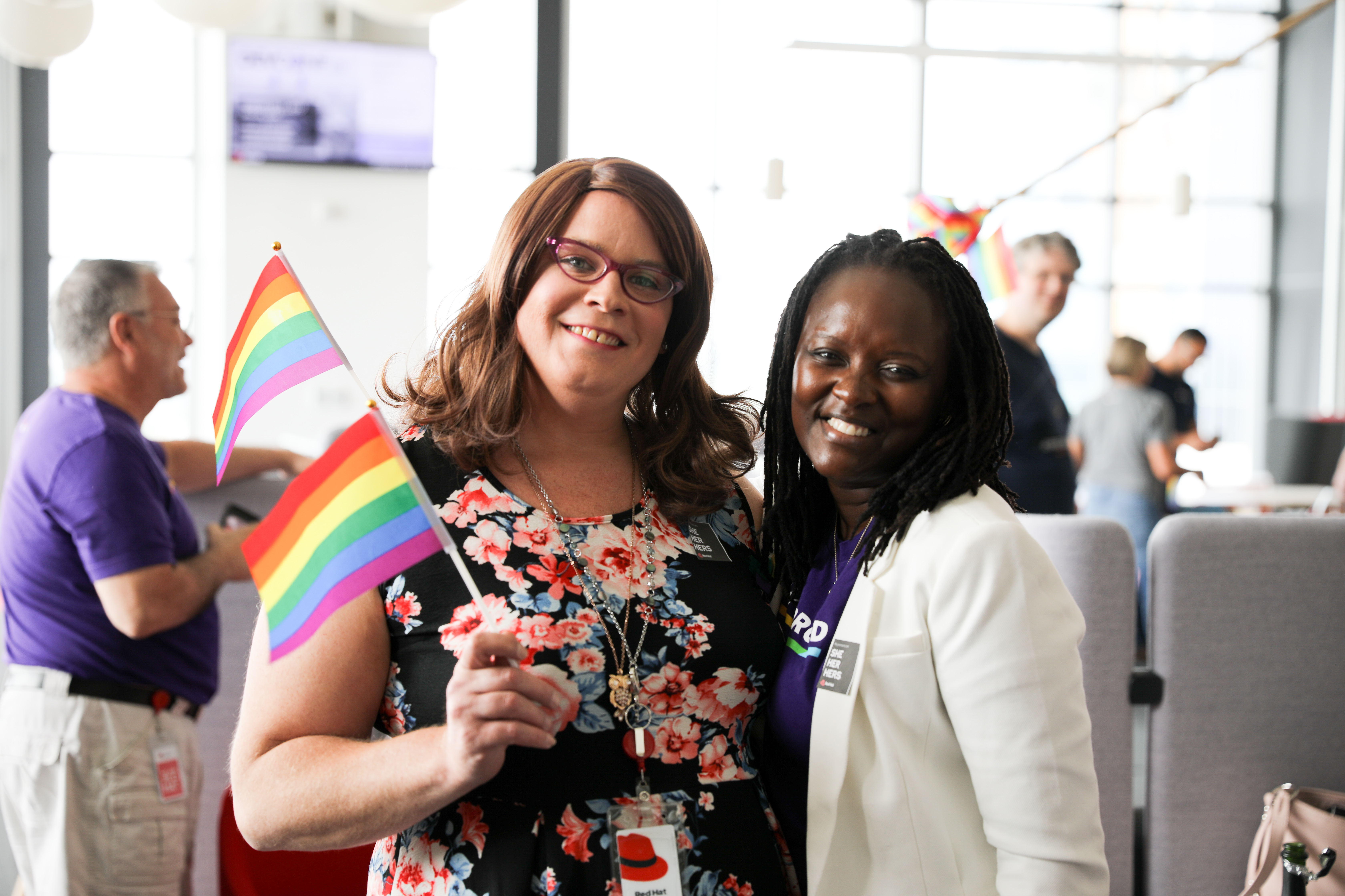 two associates, one of whom is Black, and the other of whom is holding a pride flag